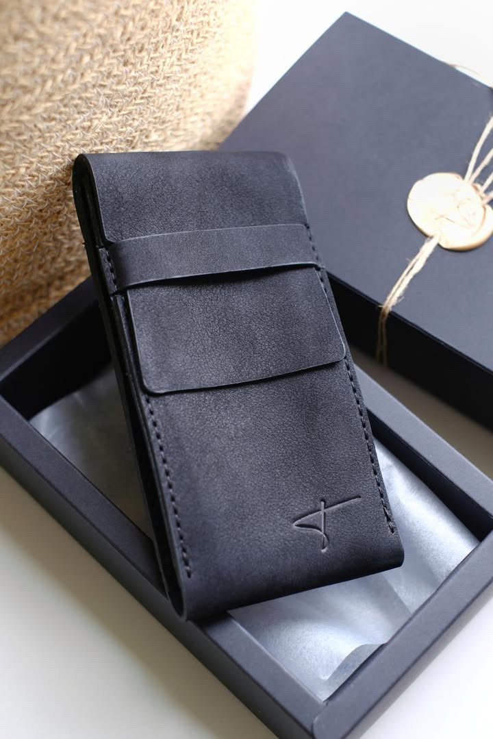 Black suede watch pouch leaning against a black Talecraft box with a wax seal